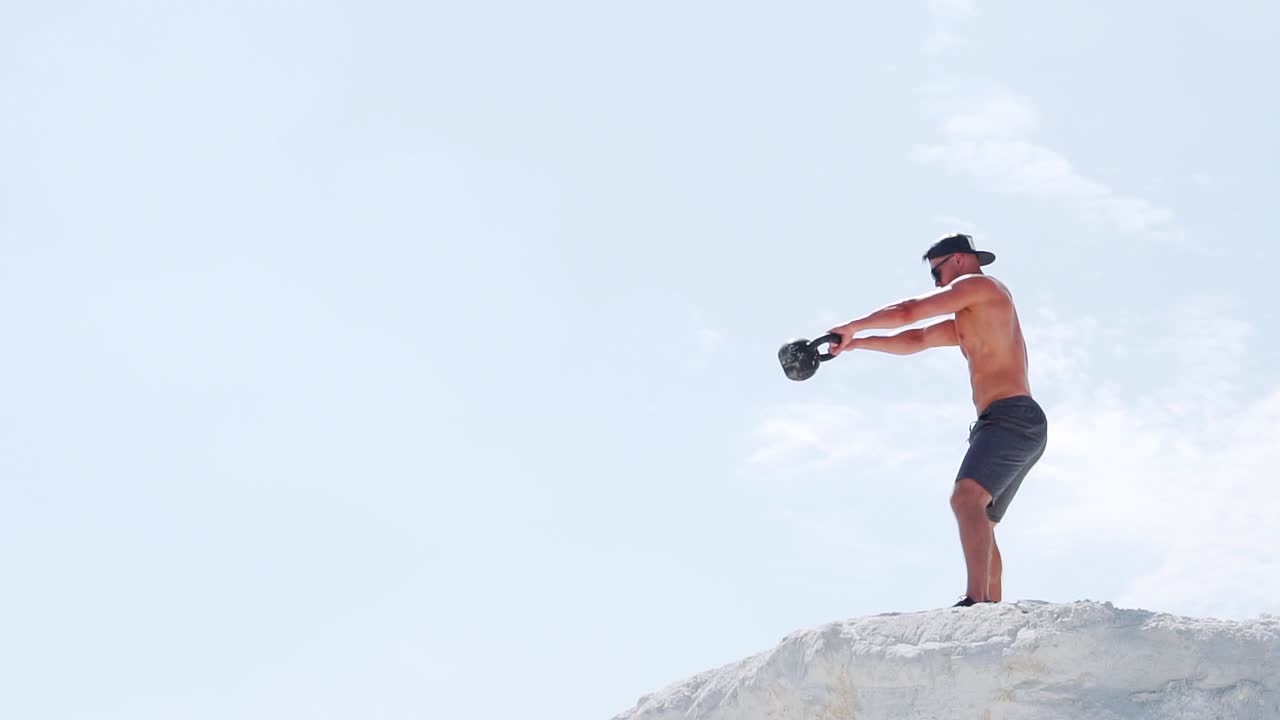 Slow motion: Man doing exercise with kettlebell in nature. fitness athletes men training muscular bodybuilders using kettlebell weights