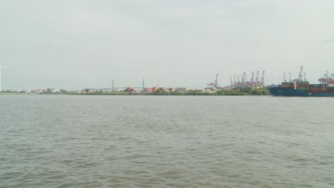 Ships-Passing-Through-Busy-Harbor-Of-Hamburg,-Big-Bridge-In-The-Background,-Germany