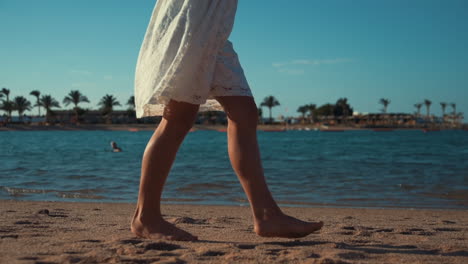 barefoot unrecognizable girl leaving footprints on sand of seashore