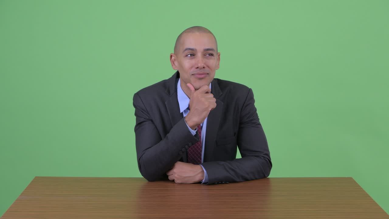 Happy handsome bald multi ethnic businessman at office desk