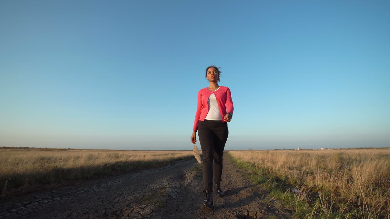 Woman Walking on a Country Road at Sunset