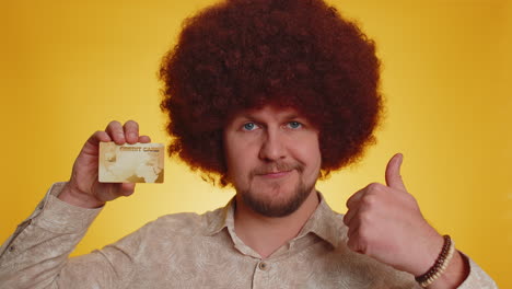 hombre con afro sosteniendo una tarjeta de crédito y sonriendo