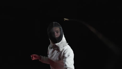 a female fencer in a fencing mask holding a sword