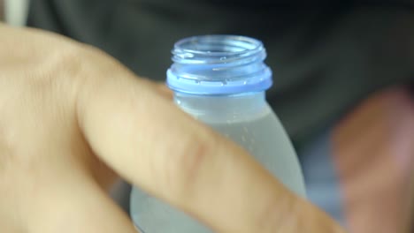 close-up of a hand opening a blue capped water bottle