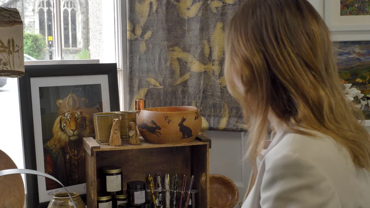 Woman looking at an AI generated tiger-human crossover piece of art for sale in a store, admiring the creative fusion