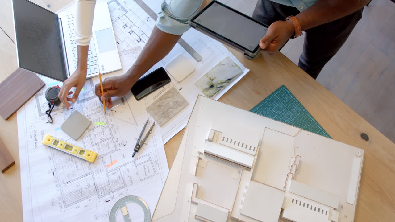 Working on architectural plans, person using tablet and pencil at desk