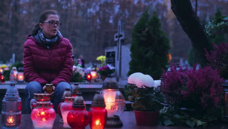 mujer en duelo en una tumba iluminada por velas encendidas