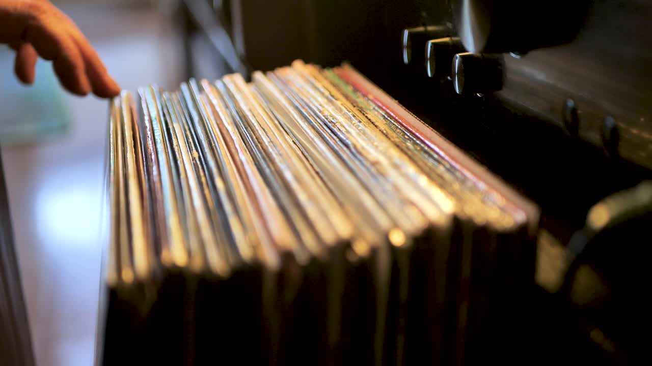 cerrar las manos del hombre hojeando discos de vinilo antiguos en casa