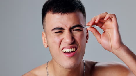 man plucking eyebrows with tweezers