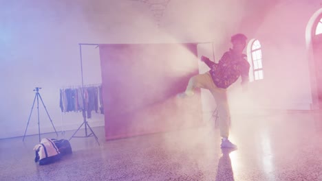 happy biracial male dancer dancing alone in dance studio, slow motion