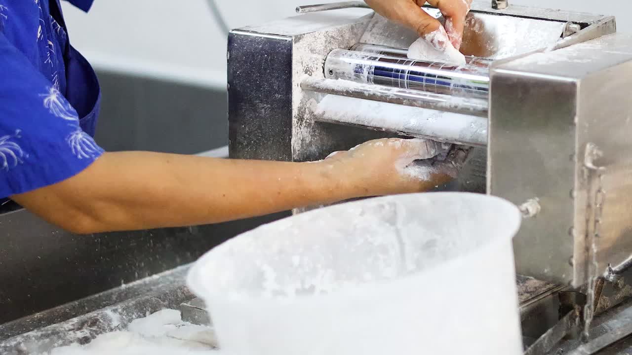 Person kneading and stretching dough on machine