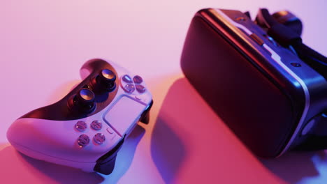 Video of close up of video game pad controller and vr headset with copy space on neon background