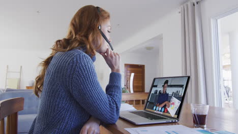 mujer caucásica usando portátil y auriculares de teléfono en videollamada con una colega