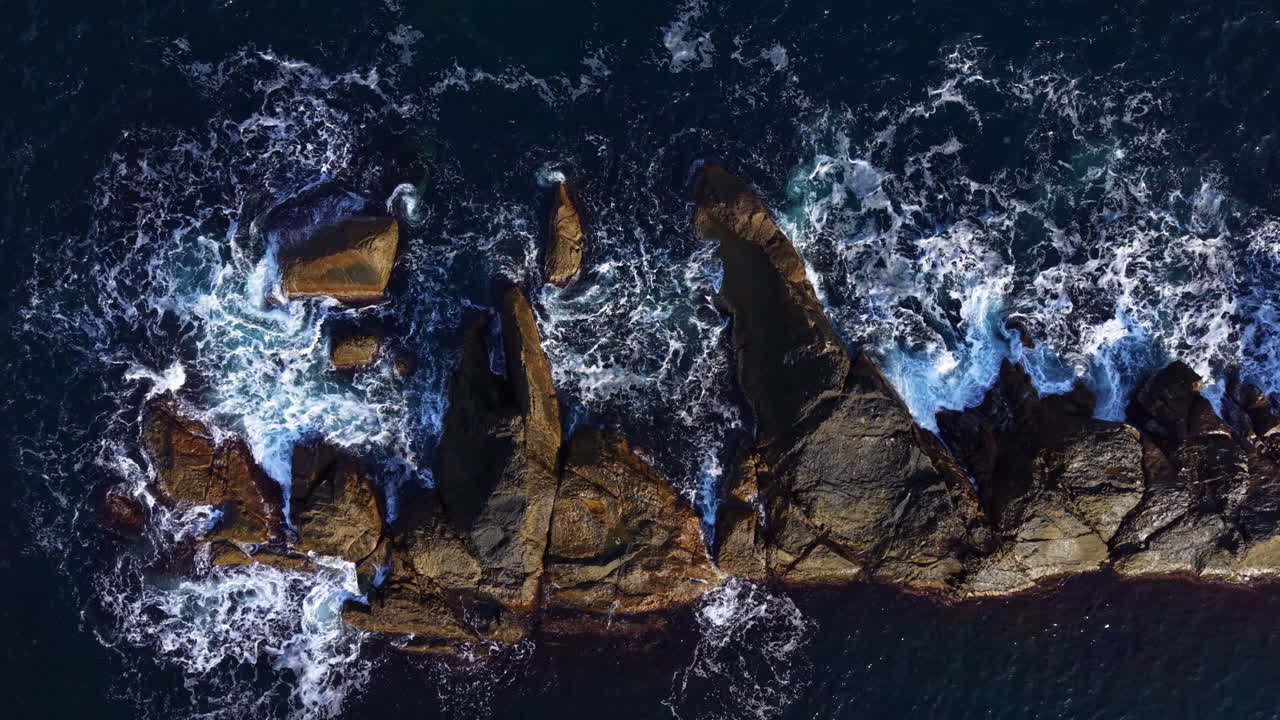Waves crashing against rugged rocks creates a beautiful dance of nature near the coast at sunset