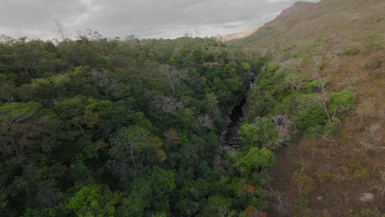 Volo FPV sopra il canyon del fiume Raizama a Chapada dos Veadeiros, Brasile, che rivela una lussureggiante foresta verde e formazioni d'acqua naturali che scorrono attraverso la natura selvaggia incontaminata