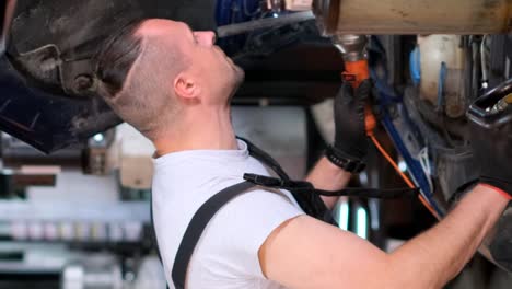mechanic working underneath a car in a garage