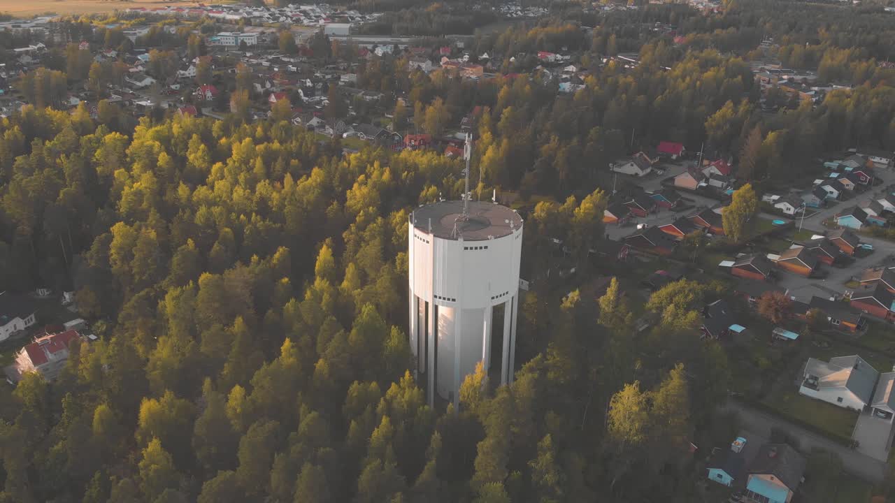 drone girando alrededor de una torre de agua al atardecer