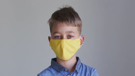 retrato de un niño caucásico con una máscara amarilla y una camisa azul