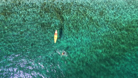 tomada aérea de arriba hacia abajo de un dron de un remo en el mar egeo turquesa, playa de andros, cícladas, grecia