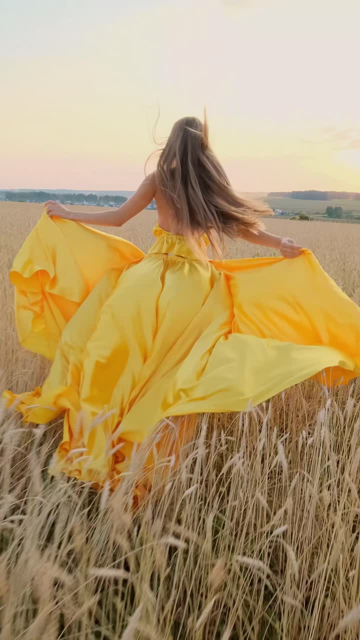 Woman in yellow dress running through wheat field at sunset