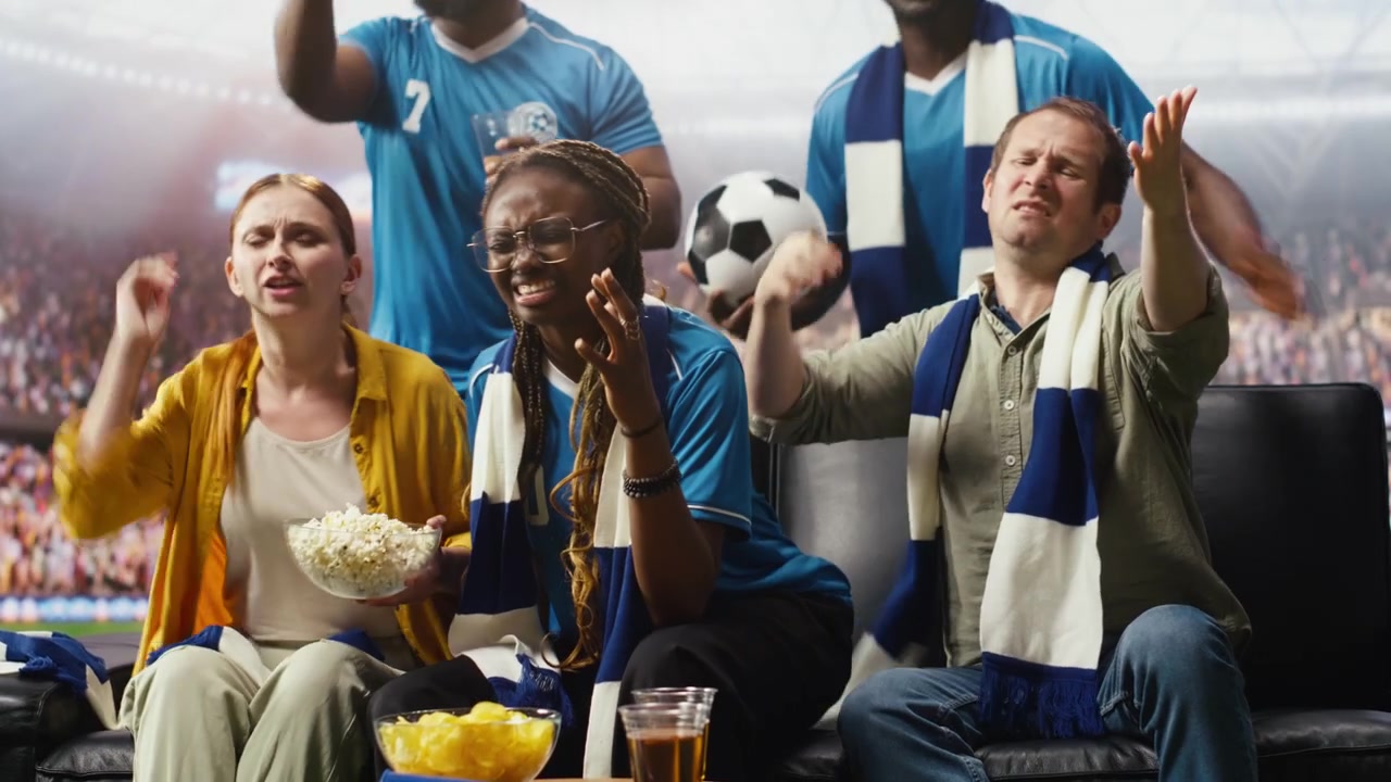 Aficionados al fútbol molestos reaccionan a un partido tenso en una transmisión de TV inmersiva.
