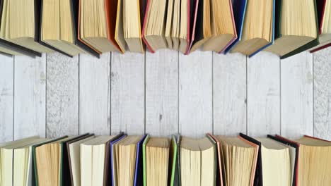 pile of vintage hardcover books appear on top ad bottom of wooden theme. stop motion flat lay