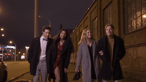 two couples of friends dressed in elegant clothes walking in the street while talking and laughing after new year's party 1