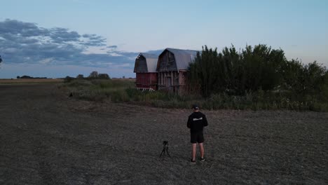 photographer taking picture of abandoned farm buildings with a camera on a small tripod