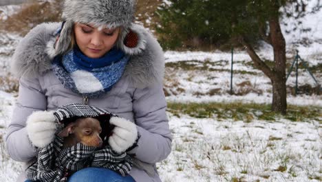 worried woman taking care of small dog during winter