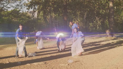 video of lights over happy diverse group picking up rubbish in countryside