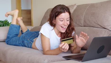 woman shopping online with laptop and credit card on couch
