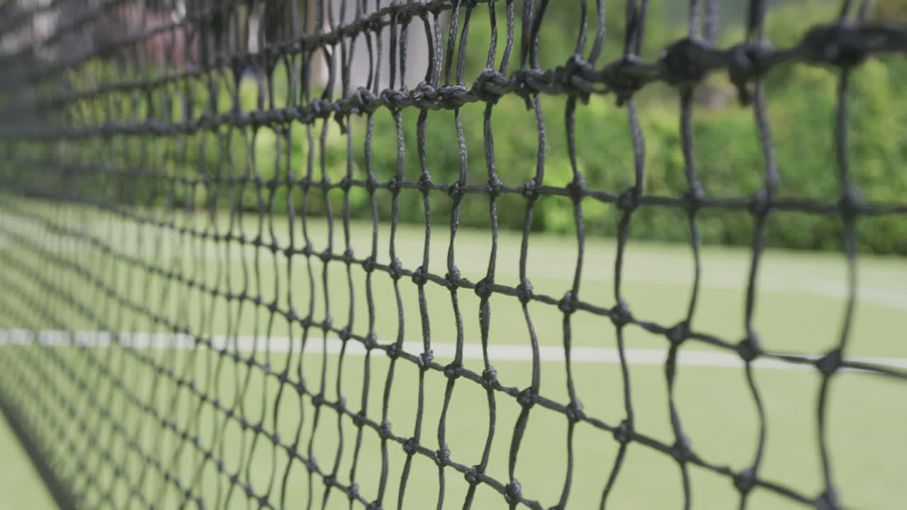Close up of tennis net and ball on tennis court in garden on sunny day