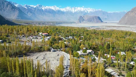 a vast panorama of a valley with mountains in the background, showcasing autumn foliage and scattered settlements in skardu