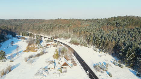 Vista-Aérea-De-Los-Coches-Que-Circulan-Por-Una-Carretera-Helada-Rodeada-De-Nieve-Invernal-Con-Ventisqueros-Durante-El-Día-Soleado-En-La-Naturaleza