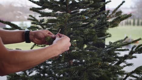 colgando decoraciones de madera en el árbol de navidad al lado de la ventana grande 4k