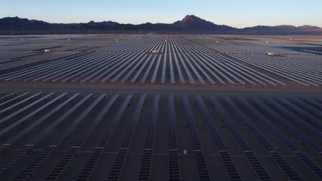 solar power plant, aerial view of massive arrays of solar panels in desert landscape at twilight, drone shot