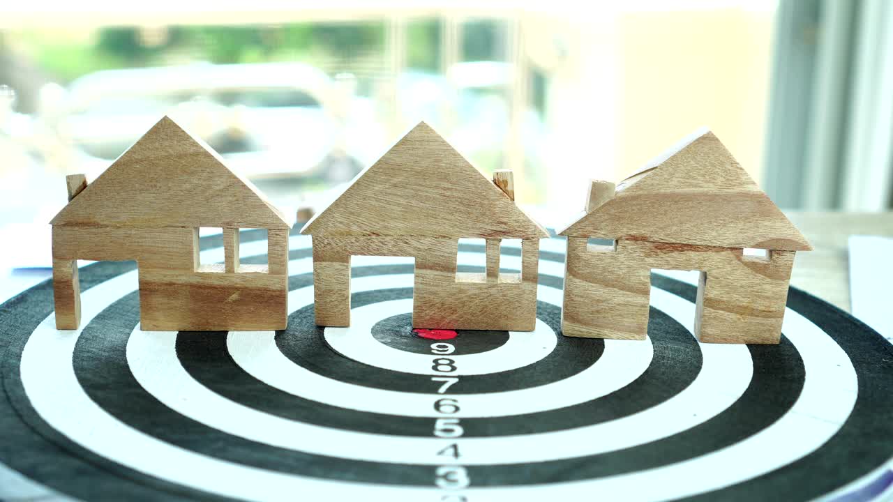 다트보드에서 집 모델을 손으로 선택하십시오. 집을 구입하기 위해 모기지 투자 자산 사업을 선택하고 돈을 절약하는 개념.