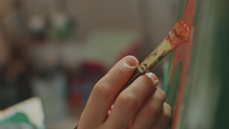 hand of artist painting fine details on canvas with brush