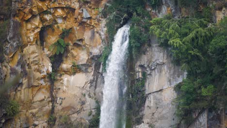 Slow-motion-shot-of-water-coming-out-of-rock-turning-into-Sipiso-Piso-Waterfall-in-North-Sumatra,-Indonesia