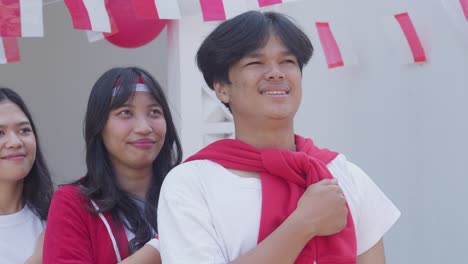 group of young man and woman with one clenched fist on their chest to showing pride and honour on indonesia independence day