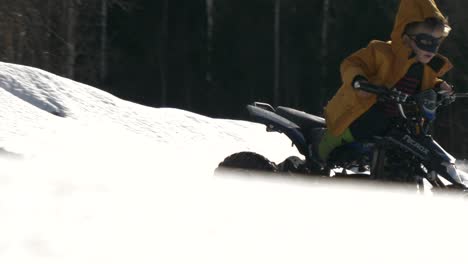 kid in superhero mask rides atv over snowy ridge, slow motion