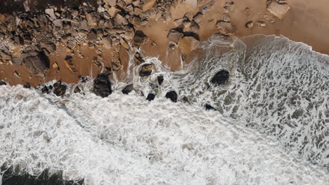 Rocky-beach-with-crashing-waves-in-Nazare,-Portugal