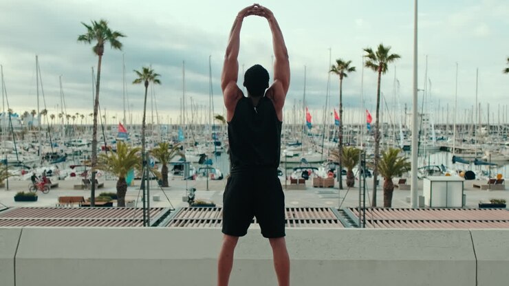 Muscular Man Stretching By The Marina