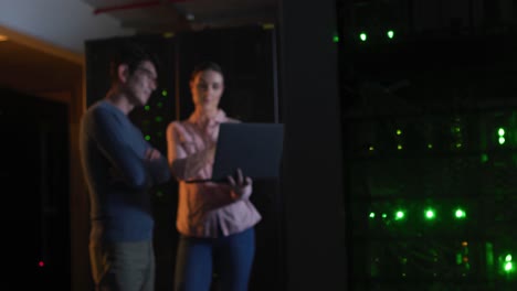 Diverse-female-and-male-it-technicians-using-laptop-checking-computer-server