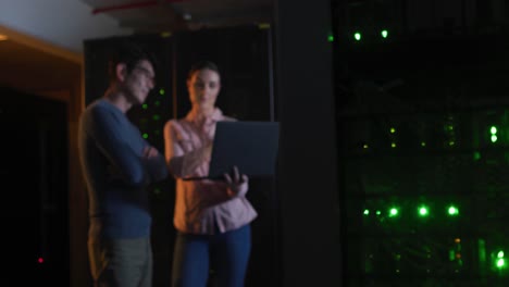 diverse female and male it technicians using laptop checking computer server