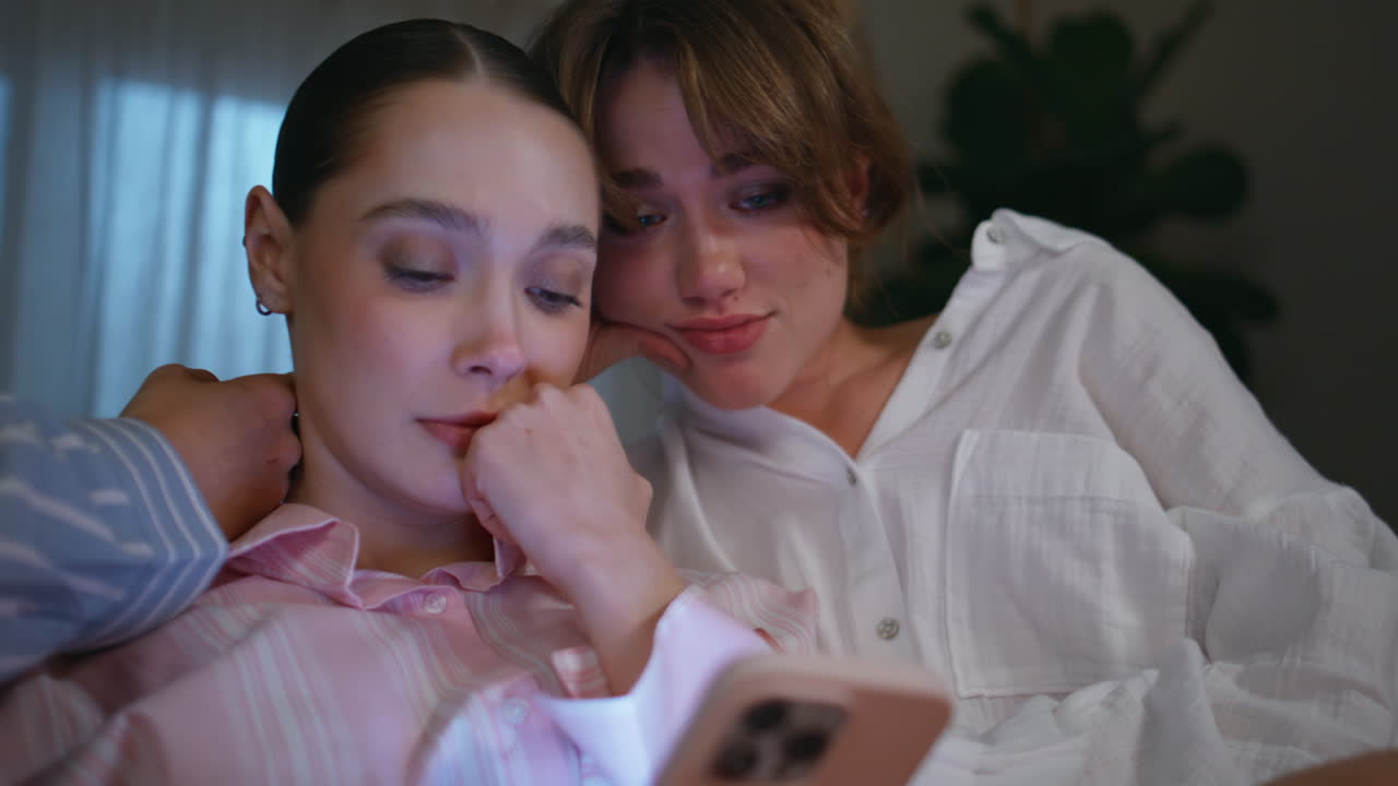 Sympathizing women comfort friend receiving bad smartphone message closeup