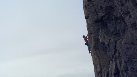 mountaineer rappelling down a large mountain without a shirt