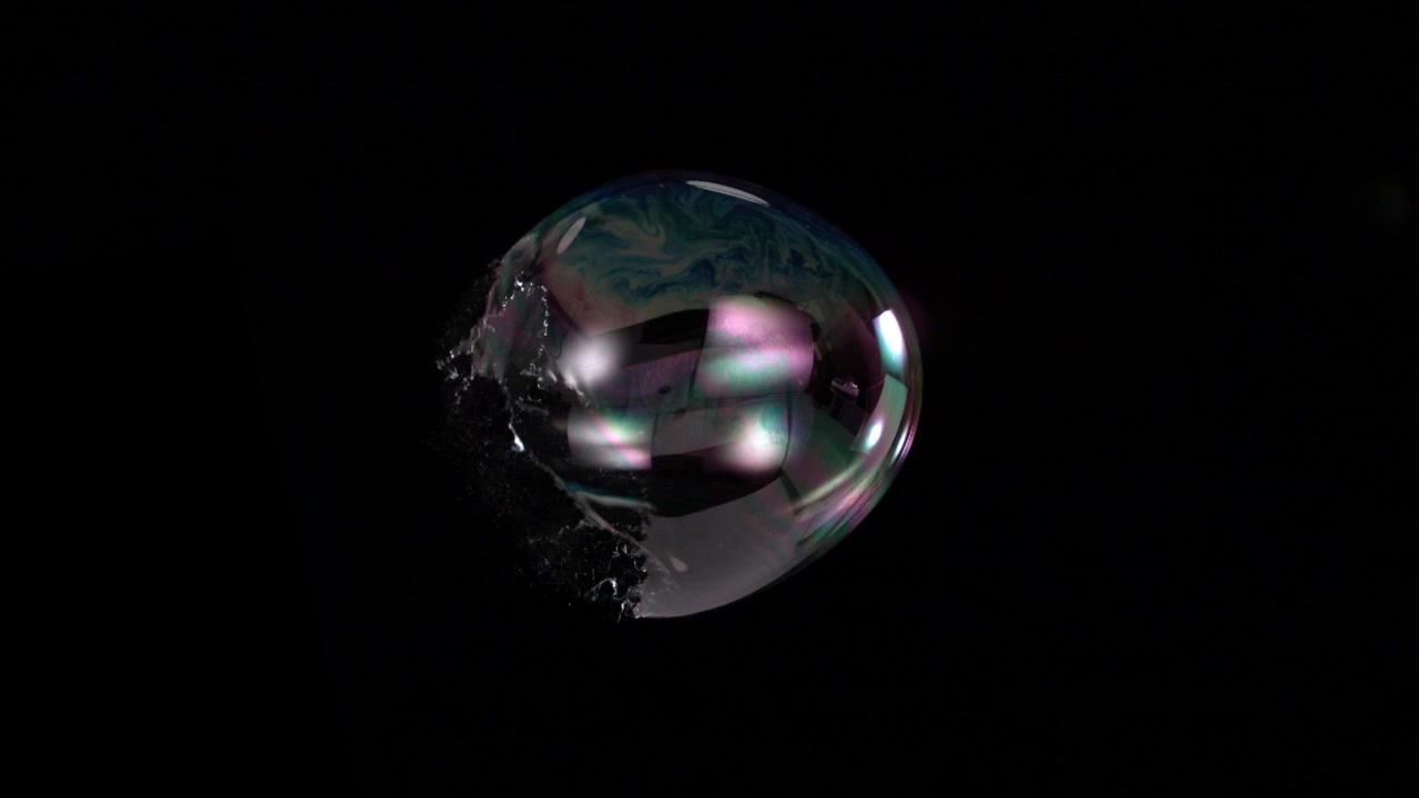 Highspeed Slowmotion captures an iridescent soap bubble bursting into a delicate liquid splash against black