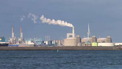 dock with factories and chimney emitting steam or smoke