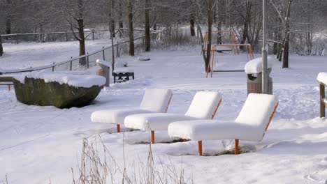 public park vacant sun lounger chairs in cold and snowy winter scenery
